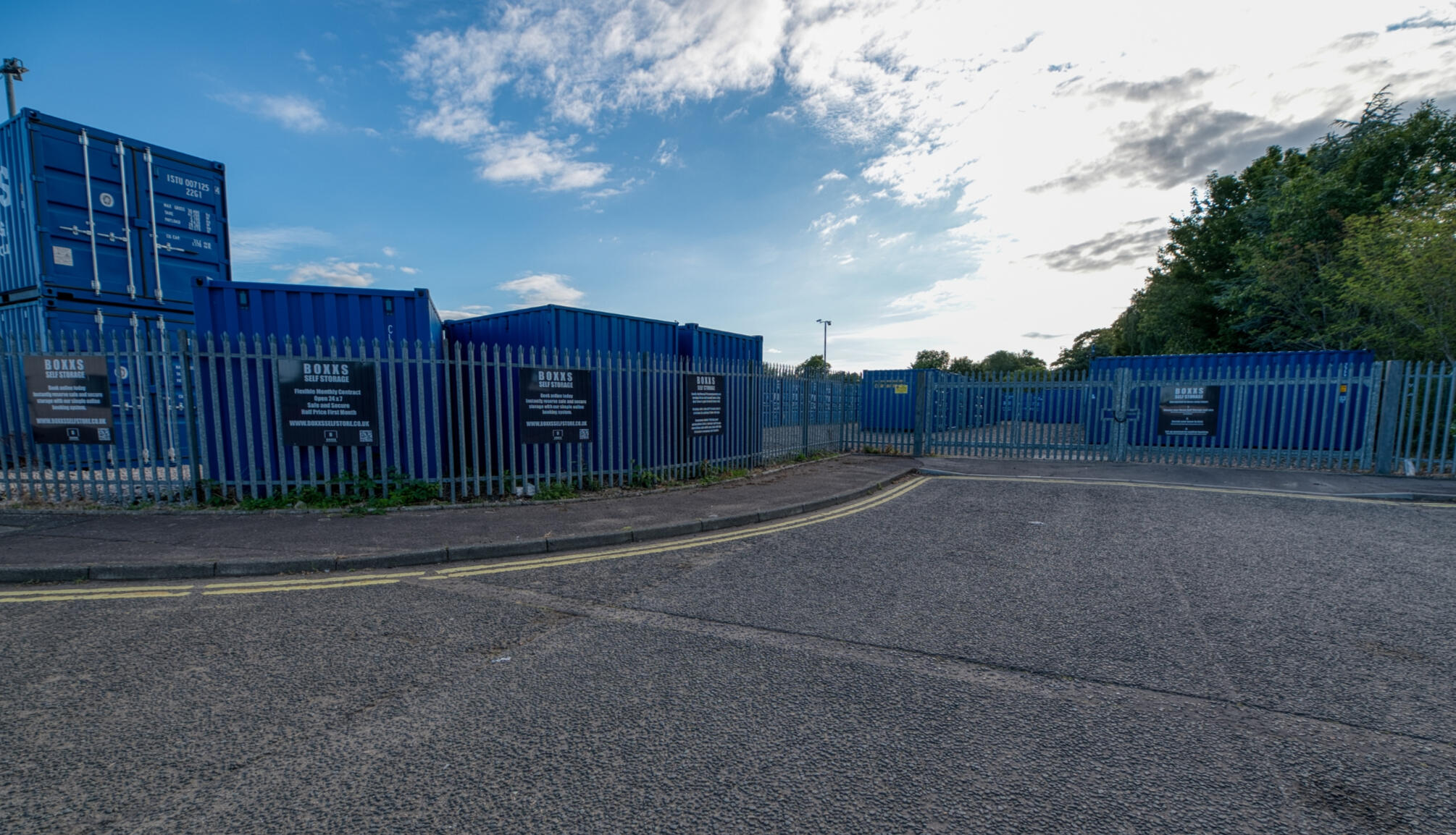 Entrance to Boxxs Self Storage in Linlithgow showing containers, secure fenced yard, and gated access for customers
